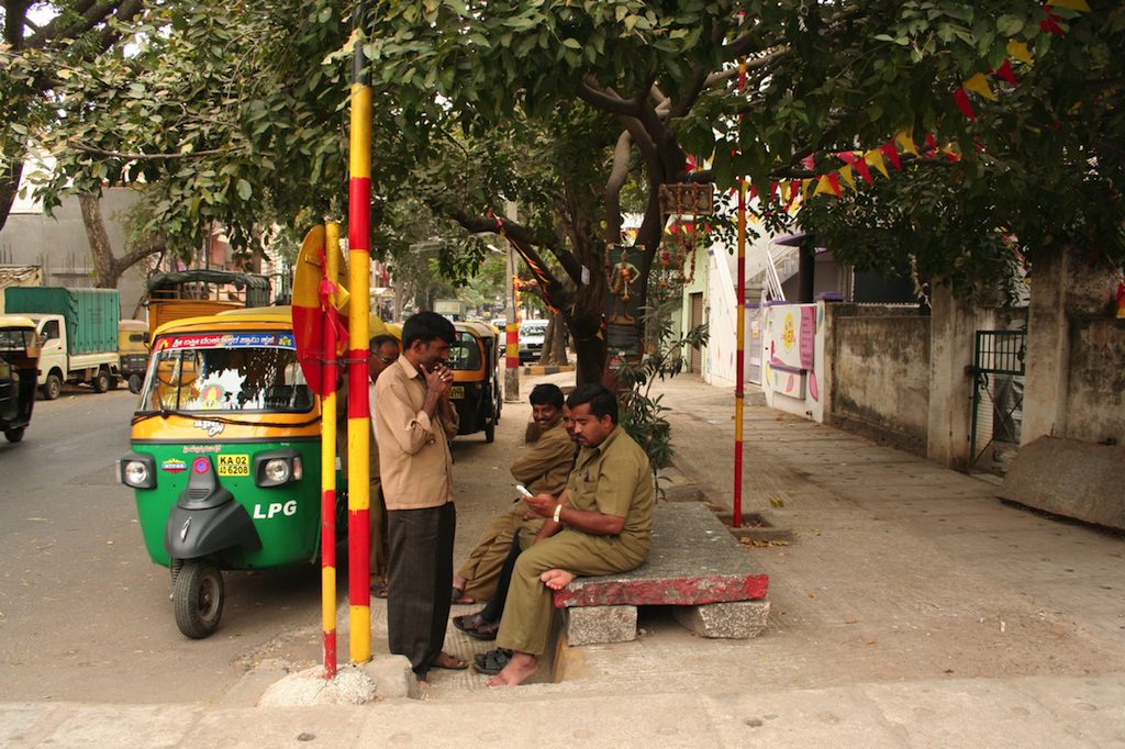 Auto-rickshaw waalas take a break while waiting for customers under a tree decorated with the colors of the Karnataka flag in Chamarajpete, Bangalore.
