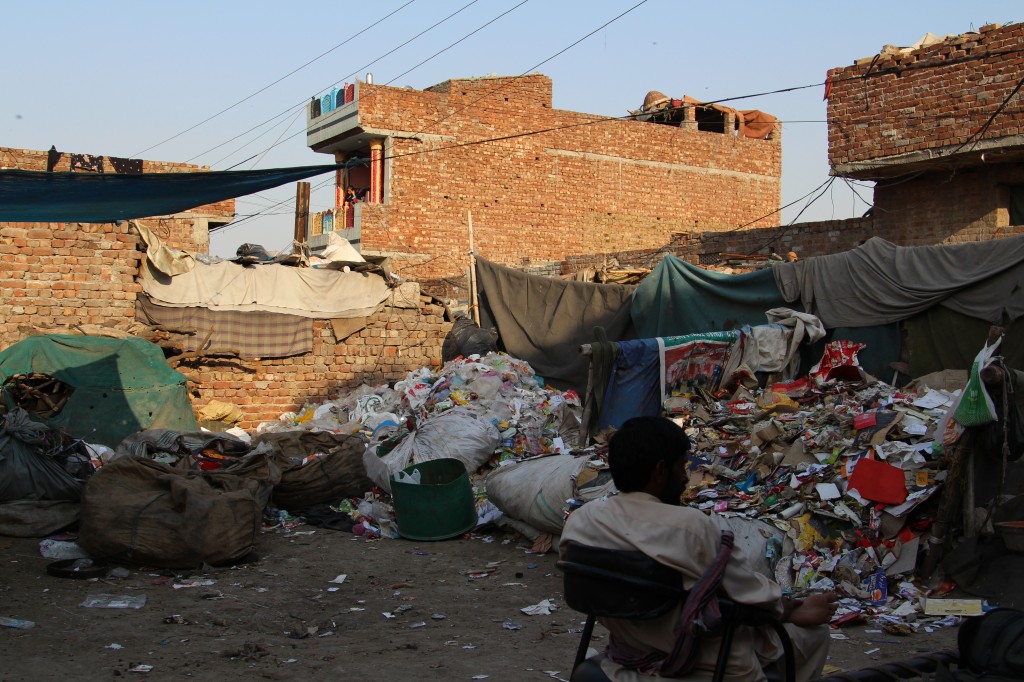 Recyclables of various kinds in khabardee located next to the jhuggee. Owner of the khabardee sitting in the foreground.